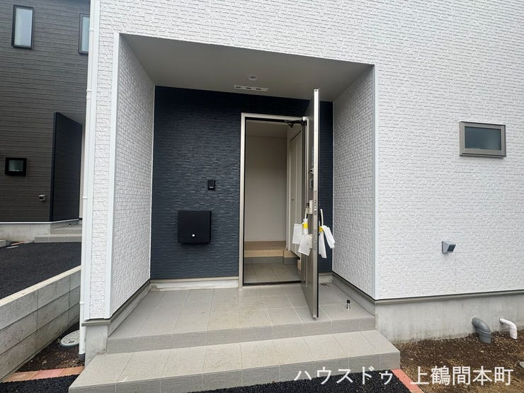 白い外壁とマッチした色調の玄関。
