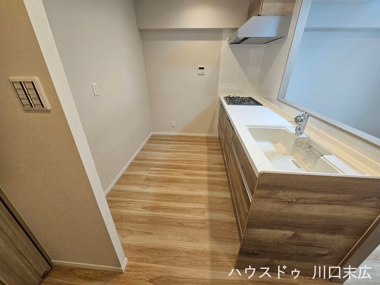 木目柄の面材が落ち着いた印象を与えるシステムキッチン。ワークトップのスペースも確保され、毎日のお料理をスムーズにサポートする機能的な造りです。