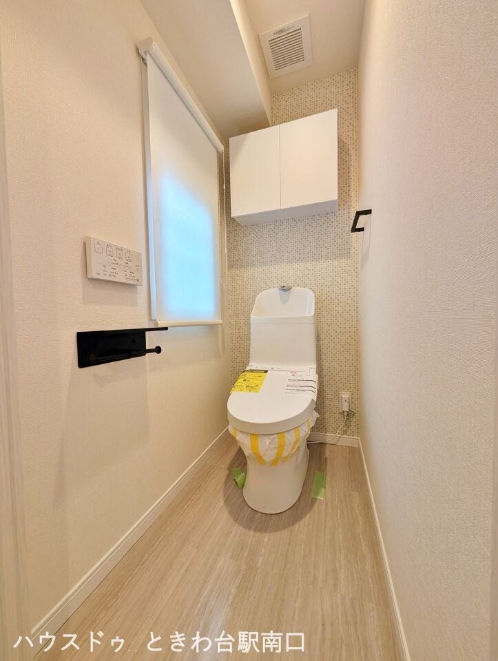 温水洗浄便座付きのトイレです。落ち着いた雰囲気のアクセントクロスを配し、上部には扉付きの吊戸棚を設置しているため、備品をすっきりと収納できます。