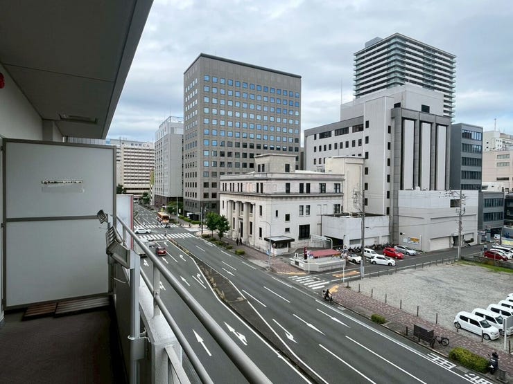 バルコニーからは、前面を通る複数車線の道路と、オフィスビルなどが立ち並ぶ市街地を見渡す景観です。正面に視界を大きく遮る建造物がなく、都市の街並みと広がる空を望む開放的な眺望となっております。