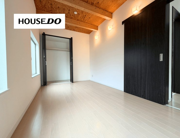 木目の天井が印象的な洋室。白い床とダークカラーの建具が映える個性的な空間です。