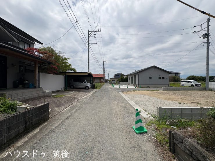 【建築前の周辺状況】南側・西側の2面が道路に接する、着工前のすっきりとした現地写真です。この敷地内に図面通りの配置で建物や外構が完成します。