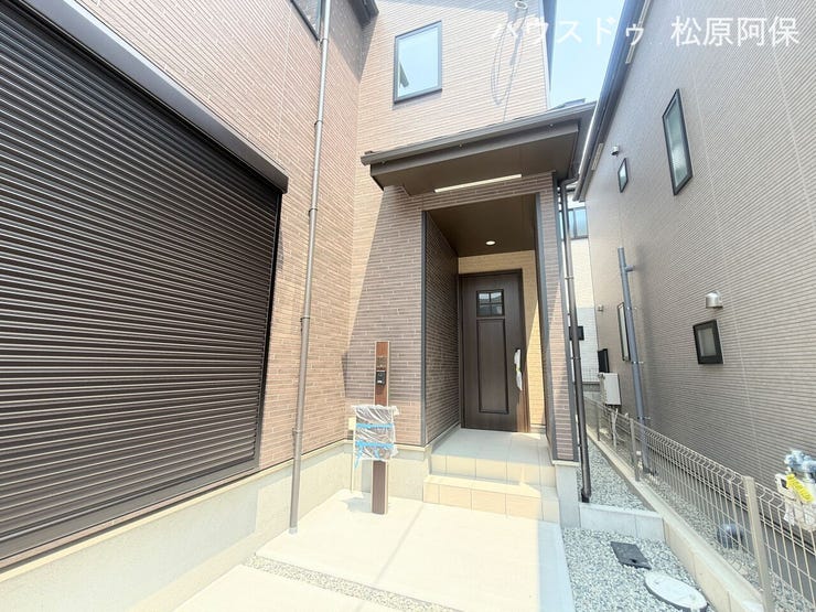 落ち着いたブラウン調の外観デザイン。屋根付きの玄関ポーチやシャッター雨戸、機能門柱を備えています。雨の日でも濡れにくく、防犯面にも配慮された設計です。
