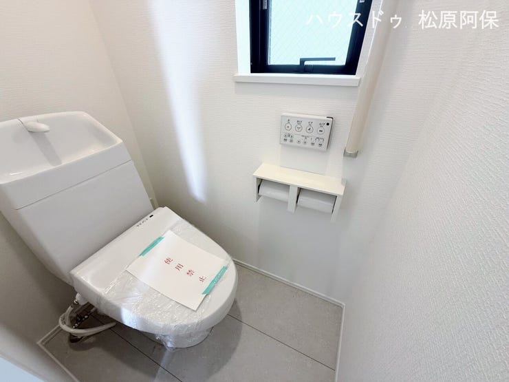 温水洗浄便座付きの快適なトイレ。手洗い付きタンクやペーパーホルダー、手すりを完備しています。窓からの採光もあり、爽やかで清潔感あふれる空間です。
