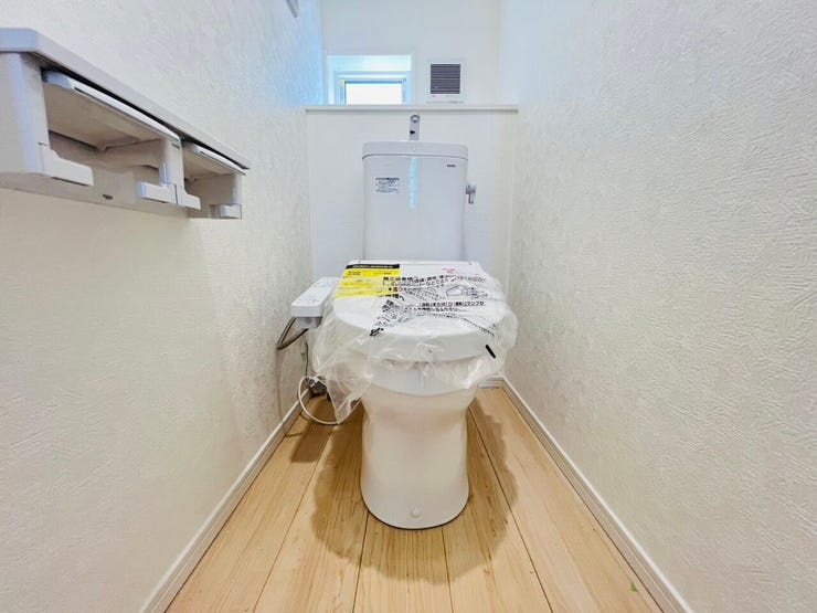 白を基調とした清潔感あふれるトイレ空間。温水洗浄便座や便利な2連ペーパーホルダーを備えています。小窓付きで換気もしやすい快適な設備を、ぜひ現地でお確かめください。