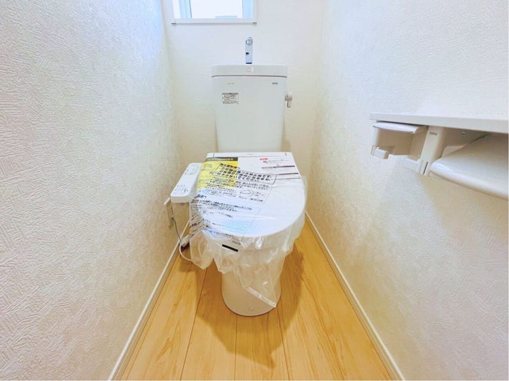 温水洗浄便座や手洗い、壁面埋込収納を備えたトイレ空間。奥には小窓があり自然換気も可能です。すっきりとした空間設計を、ぜひ現地でお確かめください。