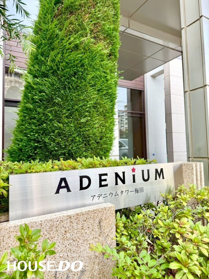 「ADENiUM 」の銘板がシンボリックなエントランスアプローチ。緑の植栽との調和が上質なマンションライフを演出しています。