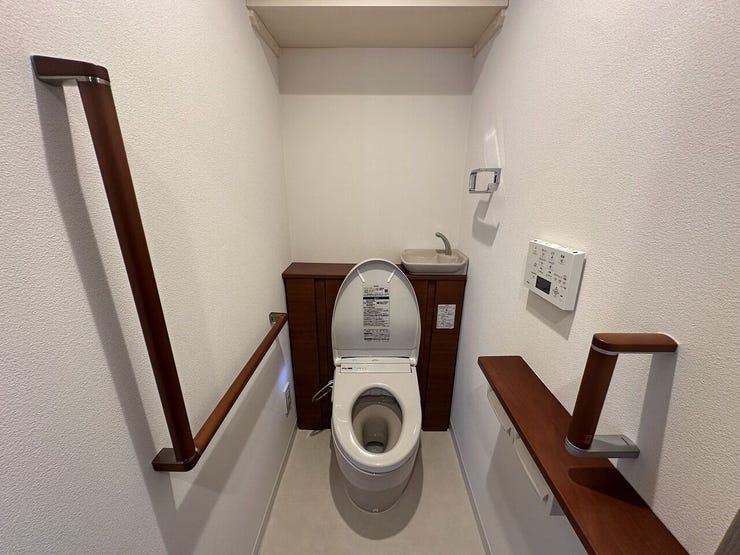 トイレは、温もりのある木目調のデザインが魅力。立ち座りをサポートする手すりや独立した手洗い器、上部収納が備わっており、どなたでも快適・便利に使える安心の空間です。