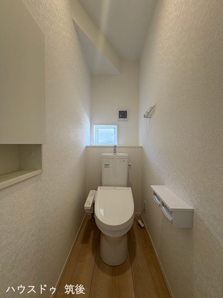 明るく清潔感のあるトイレ空間です。窓付きのため換気もスムーズ。便利な棚付きで、トイレットペーパーのストックや小物の整理も快適に行えます。