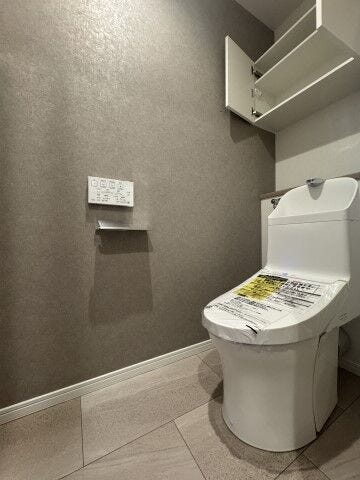 手洗い一体型ですっきりとした、温水洗浄便座付きトイレ。上部にはトイレットペーパーなどのストックに便利な吊戸棚も備わっています