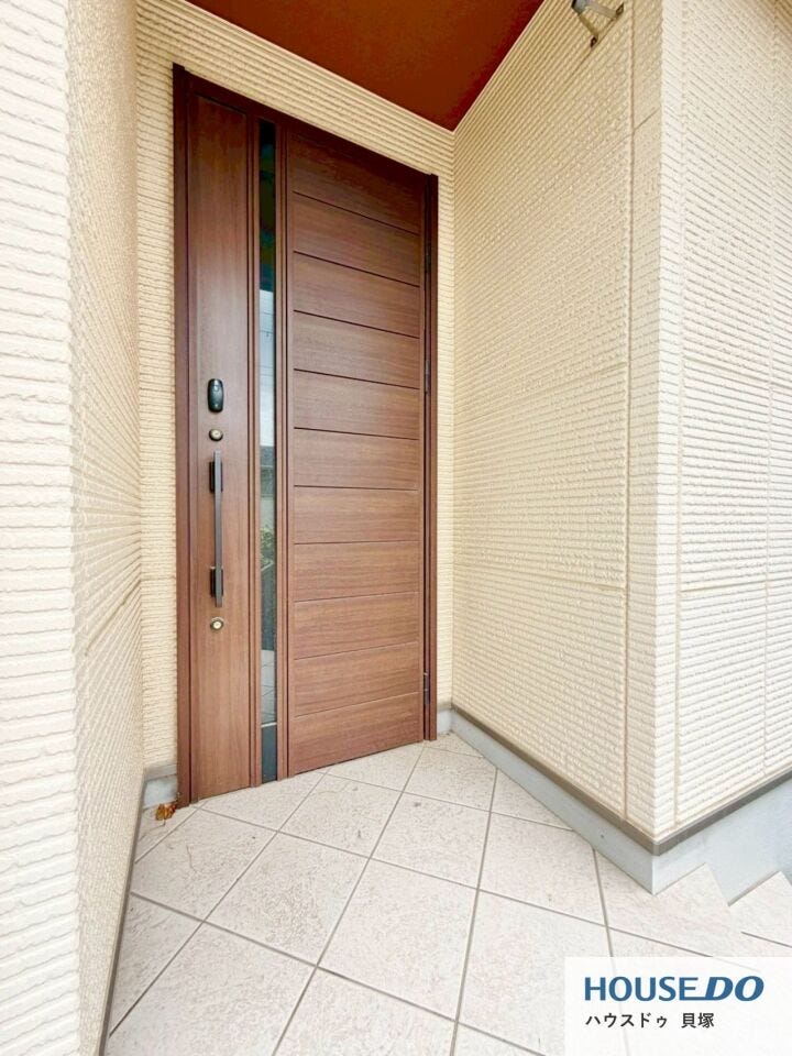 重厚感のある木目調の玄関ドアが印象的。屋根付きの玄関まわりで、雨の日の出入りも安心です。