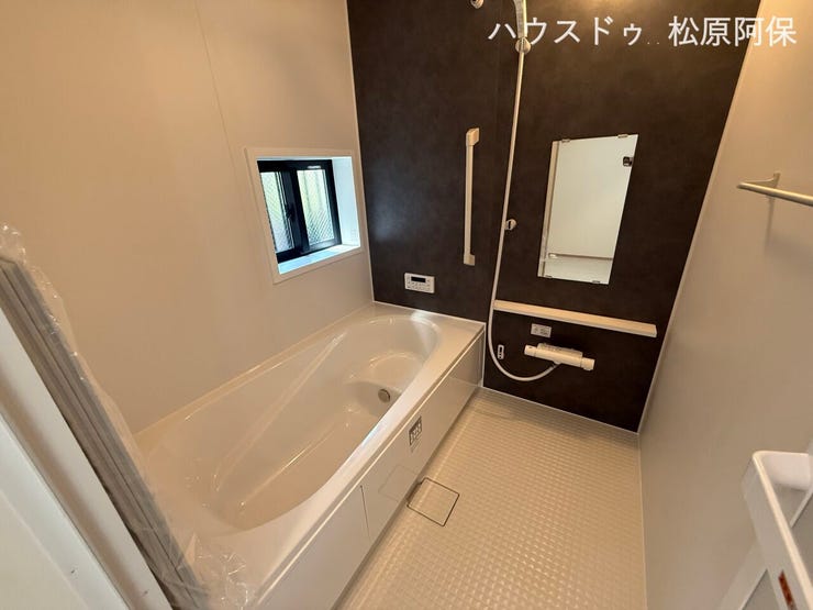 高級感のあるダークグレーのアクセントパネルがモダンな雰囲気を醸し出すバスルーム。ゆったり足を伸ばせる浴槽や採光・換気に便利な小窓、手すりを完備した上質な癒やしの空間です。