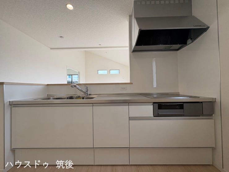 【対面式のシステムキッチン】リビングを見渡しながら調理ができるカウンタータイプです。白を基調とした清潔感のあるデザインで、上部に吊戸棚がないため、空間がすっきりと開放的に見えます。