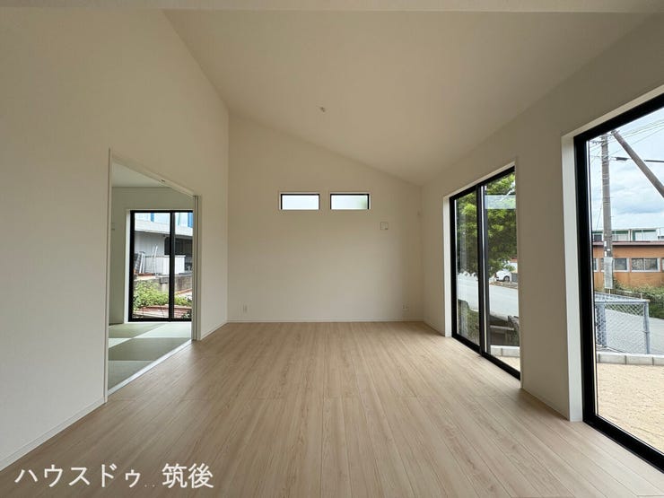【16帖LDKと隣接和室5帖】勾配天井がもたらす高い天井が特徴的なリビング。フラットに繋がる5帖の和室を開放すれば、21帖の大空間になります。複数の大きな窓から自然光がしっかりと差し込みます。