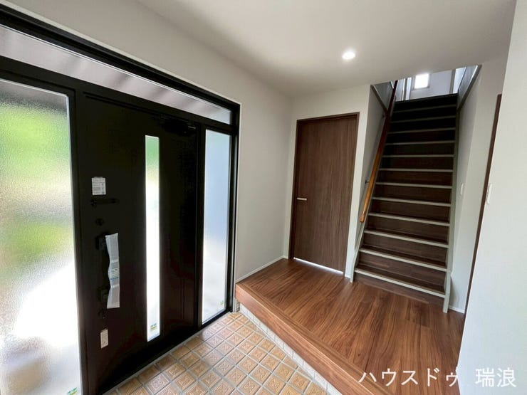 白を基調とした壁紙に、深みのある木目のフローリングが美しく引き立つ玄関です!2階へと続く階段がすぐ目の前にあり、帰宅したご家族の気配を自然と感じられます。明るくすっきりとした開放感のある空間です♪