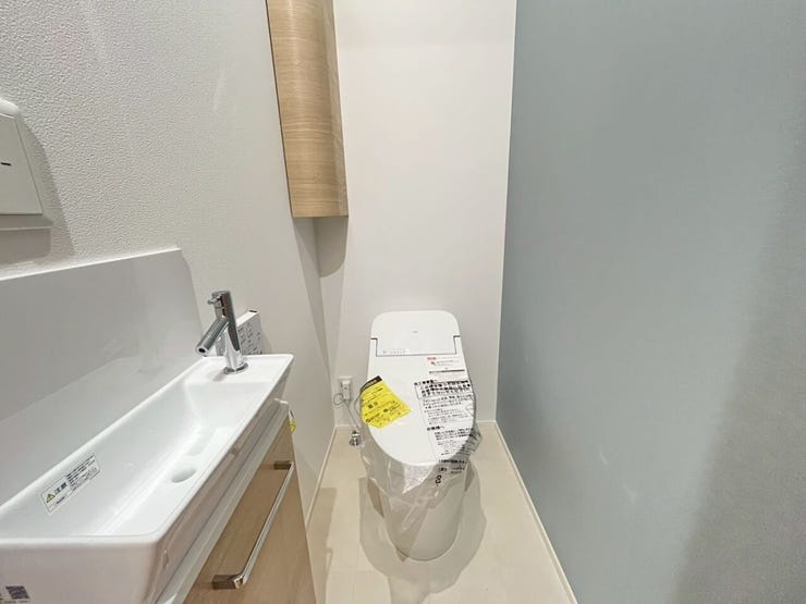 1階トイレ
独立した手洗い器が設置されたトイレ空間です。。手洗い器の下部やコーナー部分に木目調の収納設備が備わった、手入れのしやすい設備仕様です。