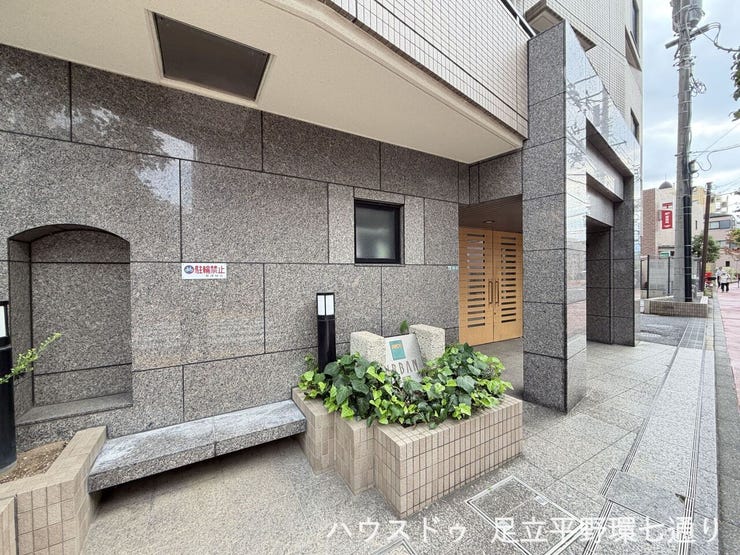 重厚感のある石調の外壁と植栽が、落ち着いた雰囲気を演出します。