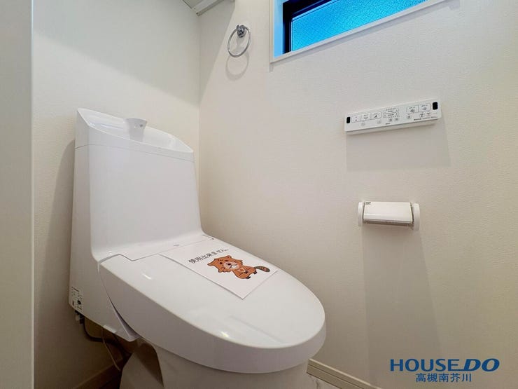 清潔感あふれるホワイト調のトイレです。壁面にリモコンや小窓を備え、衛生面や通気性にも配慮された快適空間です。