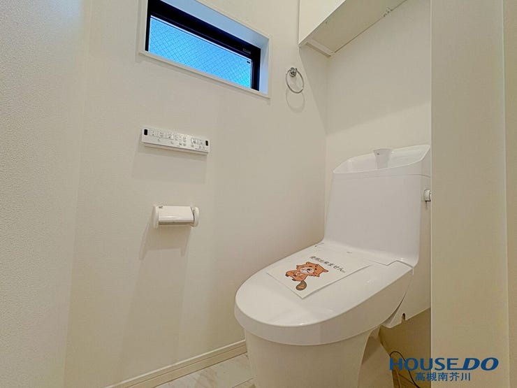 温水洗浄便座を装備した清潔感あるトイレです。上部には扉付き棚があり、小物をすっきり収納できます。