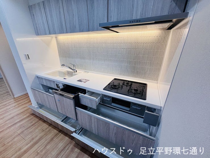 木目調のシステムキッチンに収納充実。手元を照らす照明付きで作業しやすい空間です。