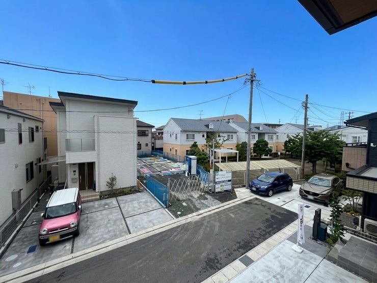 バルコニーからの眺望です。前面道路や周囲の住宅の状況を映しています。近隣に高い建物がなく、空の視界が広がる環境です。隣地との距離や周辺環境の配置を示す風景です。