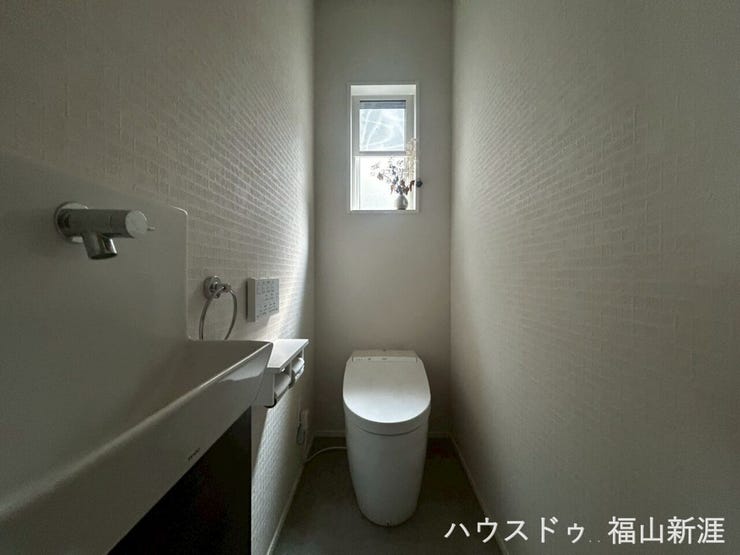 手洗いカウンター付きの清潔感あるトイレ。窓付きで自然換気ができ、明るく快適な空間となっています。
