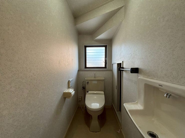 リフォーム前写真:寒い冬でも安心の温水洗浄便座のトイレです♪便器の右側に階段下のスペースを活かした収納があります♪