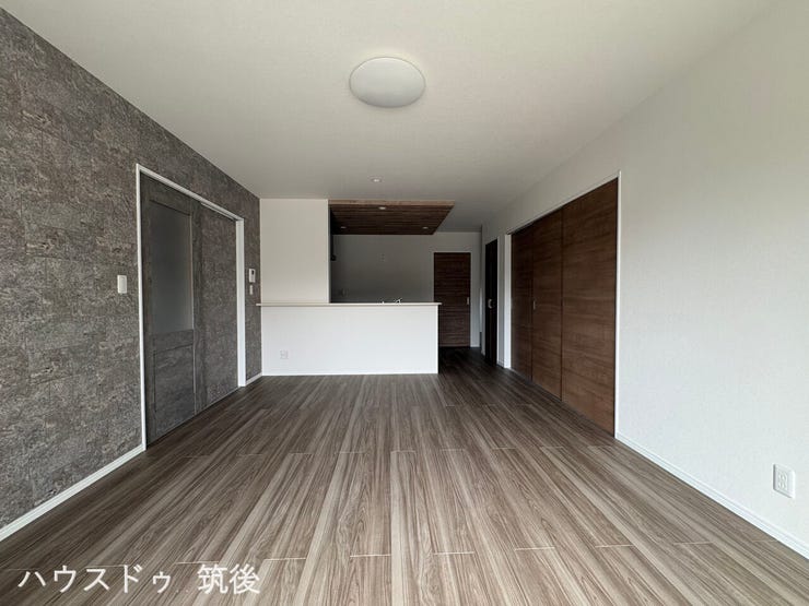 【対面キッチンのあるLDK】ご家族との会話が弾む対面式キッチンを採用した16帖のLDK。落ち着いた木目調のフローリングやアクセントクロスが特徴です。