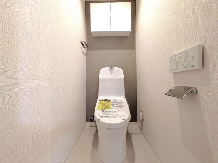 ■温水洗浄便座付きトイレ■
白を基調とした内装に、おしゃれなアクセントクロスが映える落ち着いた空間です。上部にはトイレットペーパーなどのストックをスッキリ隠して収納できる、扉付きの棚を備えています。