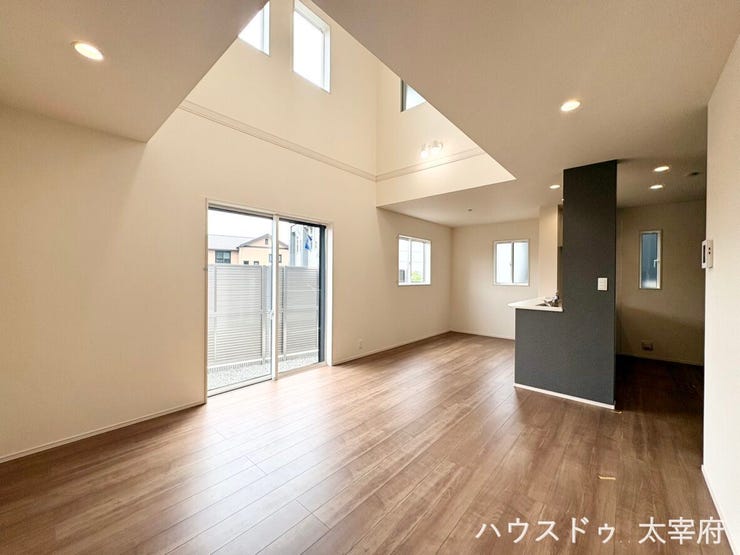 【リビング】
開放感あふれる吹き抜けと明るい光が差し込む大きな窓が魅力のLDK。ダークトーンの対面キッチンがアクセントになり、おしゃれで広々とした空間を演出しています。