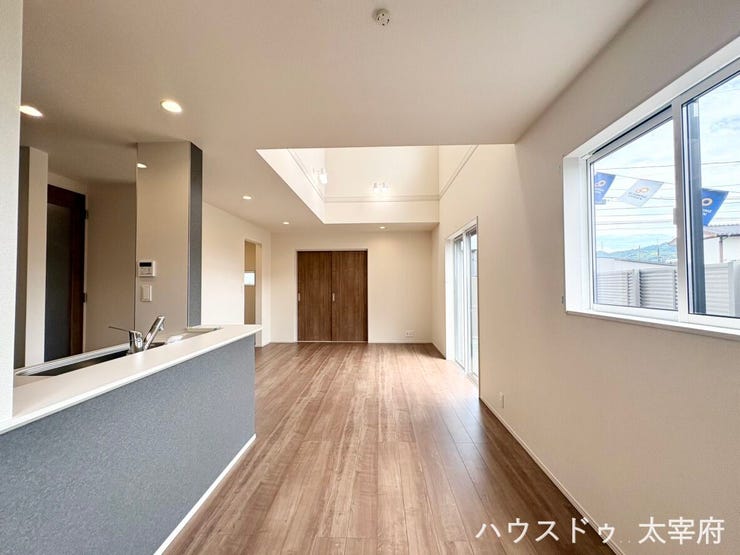 開放的な吹き抜けと明るい陽光が差し込む大きな窓が魅力のLDK。アクセントクロスがお洒落な対面式キッチンからはリビング全体が見渡せ、家族のコミュニケーションが弾む快適な空間です。