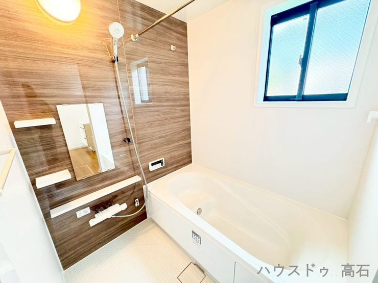 木目調のアクセントパネルが落ち着いた雰囲気を演出する、癒やしの浴室スペースです。
