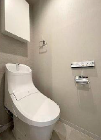 手洗い器一体型のトイレを採用。壁面には操作性の高いリモコンパネルを設置し、機能性に配慮した造りです。上部には吊り戸棚を備え、ペーパーなどの備品収納に役立ちます。