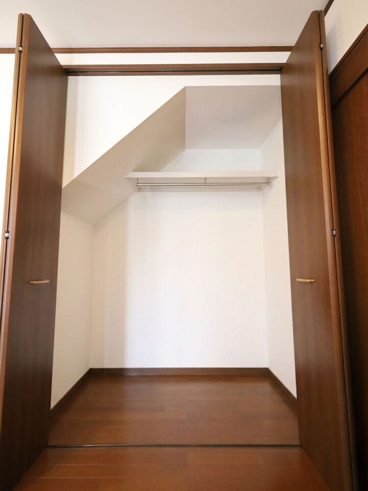 デッドスペースを有効活用した、奥行きのあるハンガーパイプ付階段下収納。※現況の物件写真に、引渡し時のイメージとしてCGによる画像処理がされています。