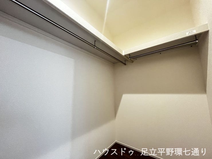 奥行きのあるウォークインクローゼット。衣類を掛けて収納できるハンガーパイプと上部棚を備えています。