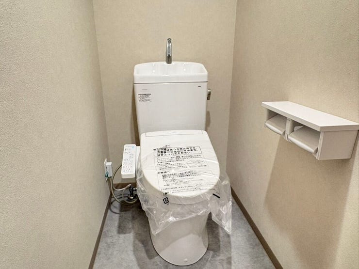 清潔感あふれる温水洗浄便座付きのトイレです。ペーパーホルダーの上には小物を置ける棚があり、芳香剤を置いたりスマホを一時的に置いたりと使い勝手も良好。毎日使う場所だからこそ、シンプルで快適な空間ですよ