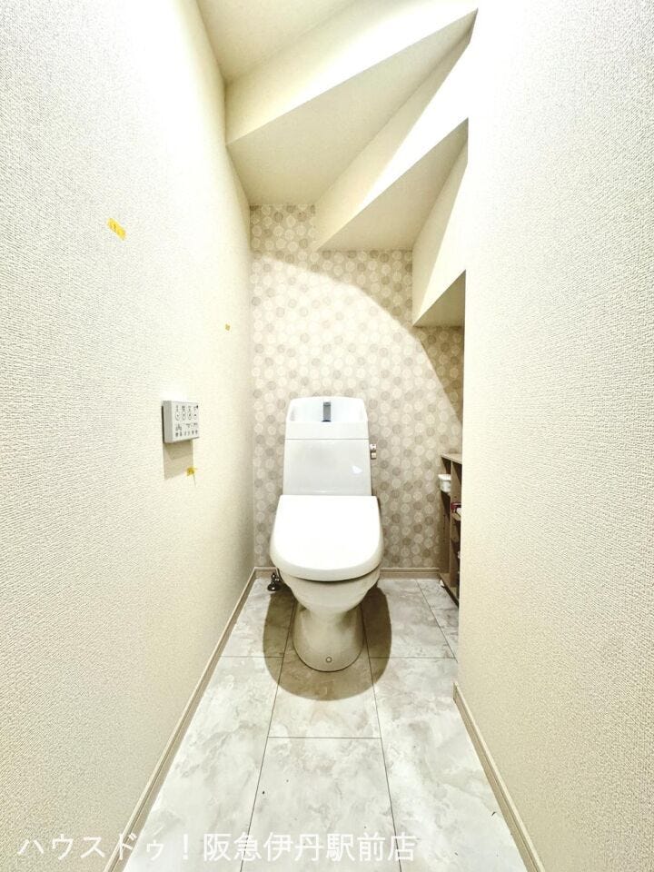 温水洗浄便座完備のトイレ。落ち着いたデザインクロスでくつろげる空間。