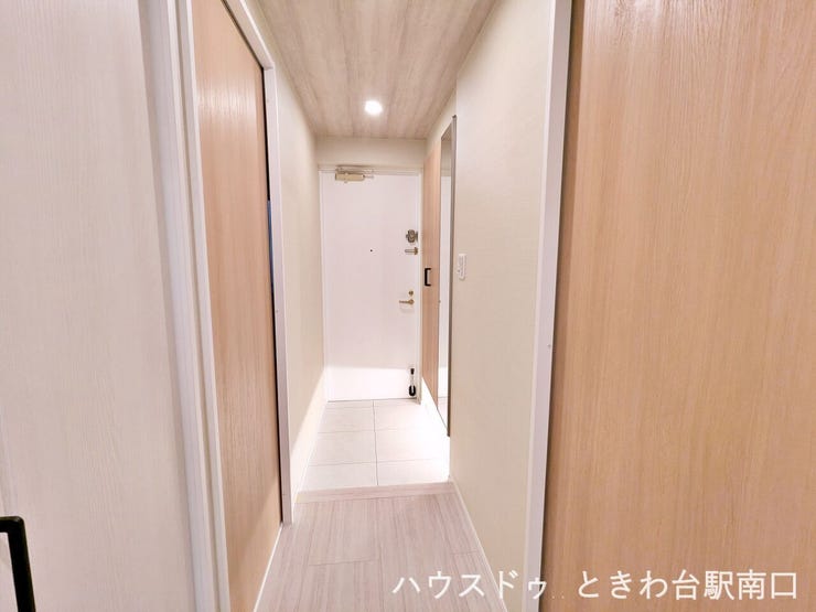 白を基調とした清潔感のある廊下。木目のドアがアクセントとなり、お部屋への期待感を高める温かみのあるアプローチです。