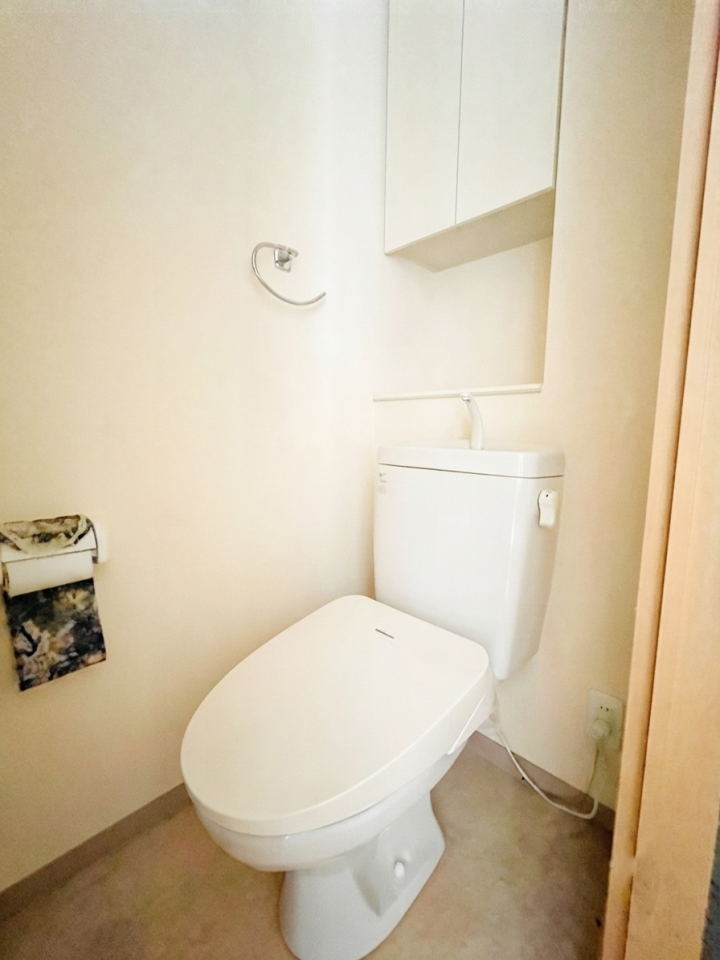 ウォシュレット付きで快適なトイレスペースです。上部には吊戸棚があり、生活感を出さずに収納できます。シンプルで飽きのこないデザインと、手入れのしやすい仕様で、いつでも清潔にご利用いただけます。