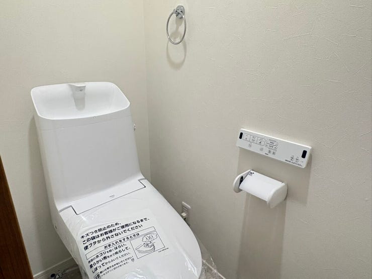 白を基調とした清潔感のあるトイレ空間には、使いやすい洗浄機能付き便座が備わっています。壁面にはリモコンやペーパーホルダーがすっきりとレイアウトされ、毎日の暮らしに心地よさを届けます。