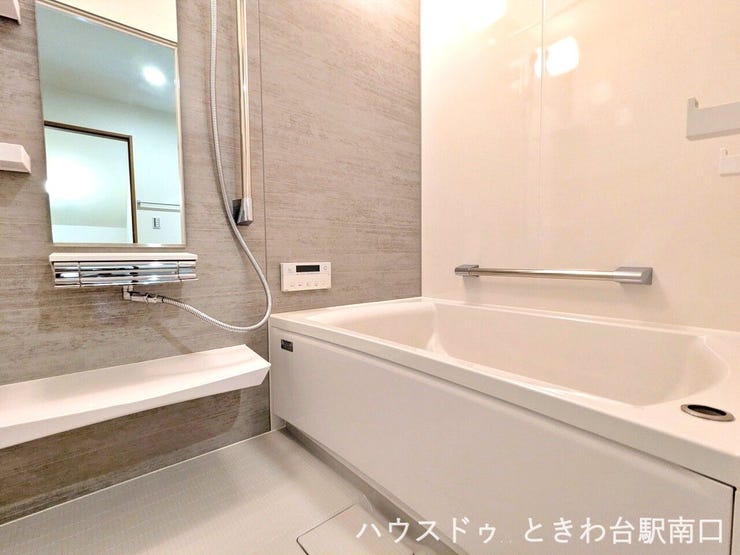 落ち着いたグレーのパネルが洗練された印象を与えるバスルームです。ゆったりとした浴槽には手すりが設置されており、立ち座りの動作をサポート。一日の疲れを癒やす心地よいリラックスタイムを提供します。