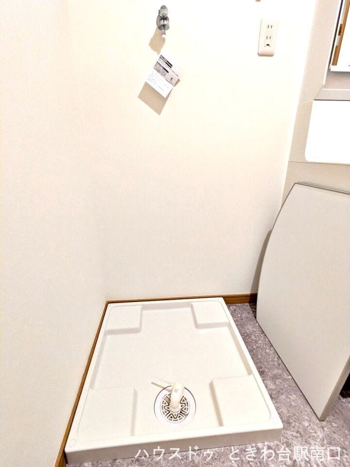洗面室内の洗濯機置き場は、お手入れのしやすい防水パンを設置しています。周囲は清潔感のある白を基調としており、無駄のない配置で家事動線もしっかりと確保された、使い勝手の良い空間です。