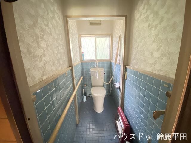 青のタイルが特徴のトイレです。壁面には手すりがついており、お子様やお年寄りの方に配慮された設計です。