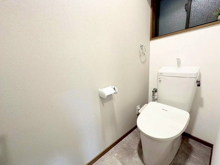 温水洗浄便座を完備した快適なトイレです。手洗い付きタンクや、使いやすい位置に配置されたペーパーホルダー、タオル掛けなど、実用的な設備をコンパクトに集約。サッと開閉できる換気用の小窓も付いています。
