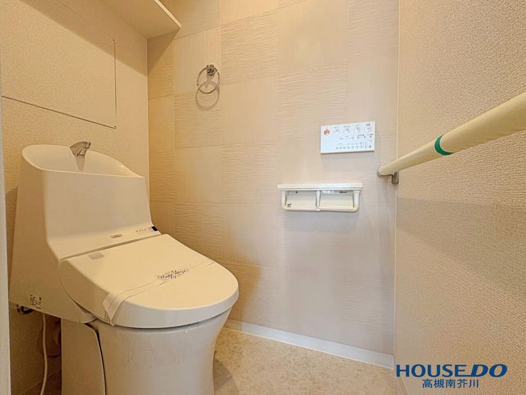 温水洗浄便座付きの清潔なトイレ空間。手すりやペーパーホルダー、上部棚も備わっており、快適にお使いいただけます。