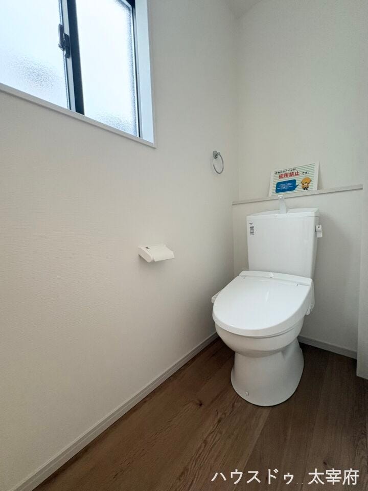 【1階トイレ】温かみのある木目調フロアと白を基調とした清潔感あふれるトイレ空間です。便利な温水洗浄便座を完備し、小窓から差し込む自然光が明るく、快適に使える仕様となっています。
