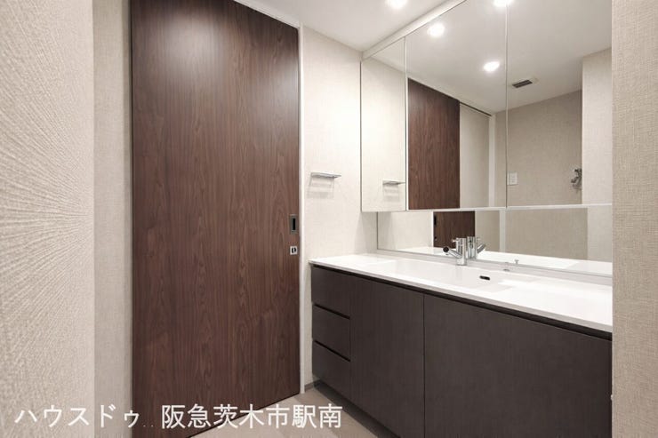 広々とした洗面化粧台。三面鏡と収納も充実しており、朝の身支度も快適に行える使い勝手の良い空間です