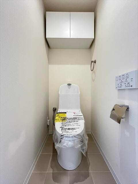 清潔感のある温水洗浄便座付きトイレ。上部には収納棚を備え、トイレットペーパーや日用品もすっきり収納できます。