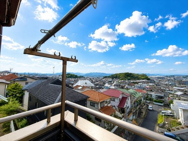 「バルコニーから街並みと山々を望む開放的な眺望。遮るものが少なく、空の広さを感じられる爽快な景色です。」