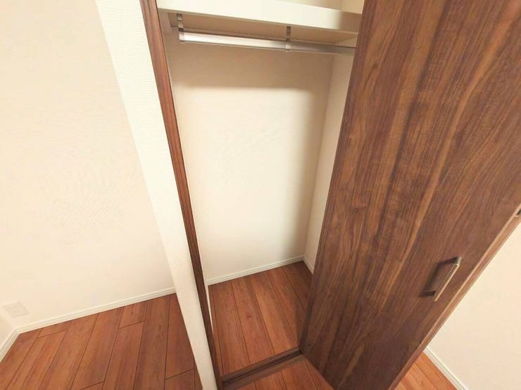 木目調の扉が落ち着いた印象の、ハンガーパイプと枕棚を備えたシンプルな収納スペースです。衣類や小物を整理でき、お部屋をすっきりと保つことができます。限られたスペースを有効に活用した、実用的な設計です